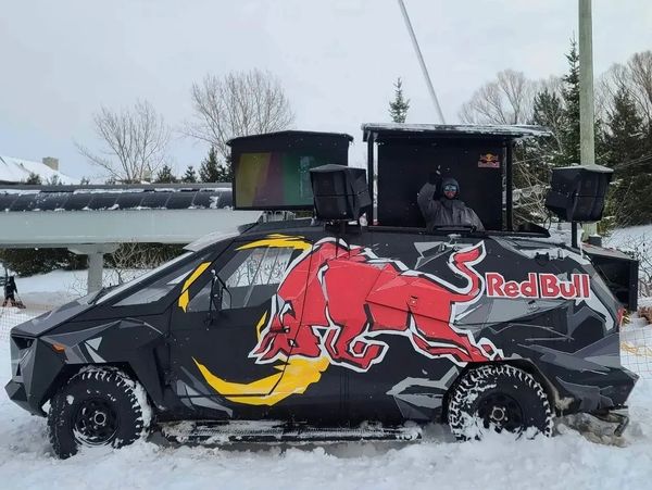 Red Bull branded vehicle in snow with a person waving from the roof.