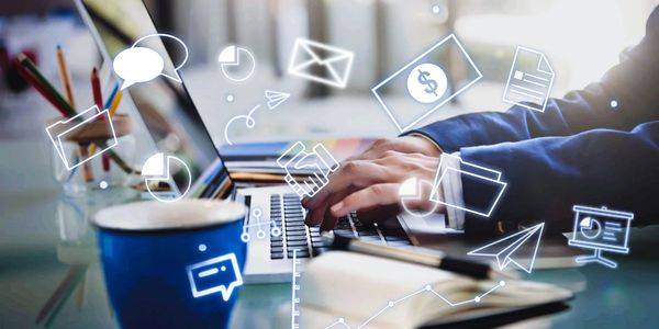 Image of man typing on laptop with a cup on the table and icons all over the page