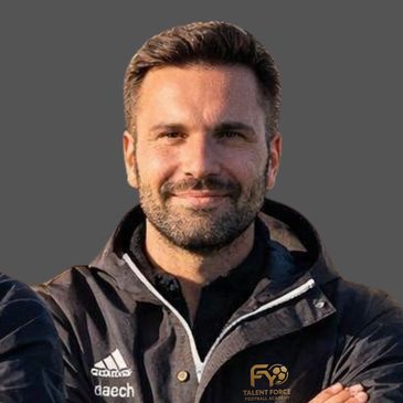 Man in black jacket with folded arms smiling at the camera.