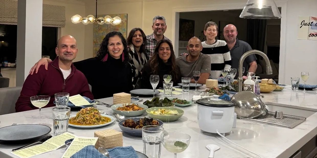 Group of friends enjoying a dinner gathering around a kitchen island.