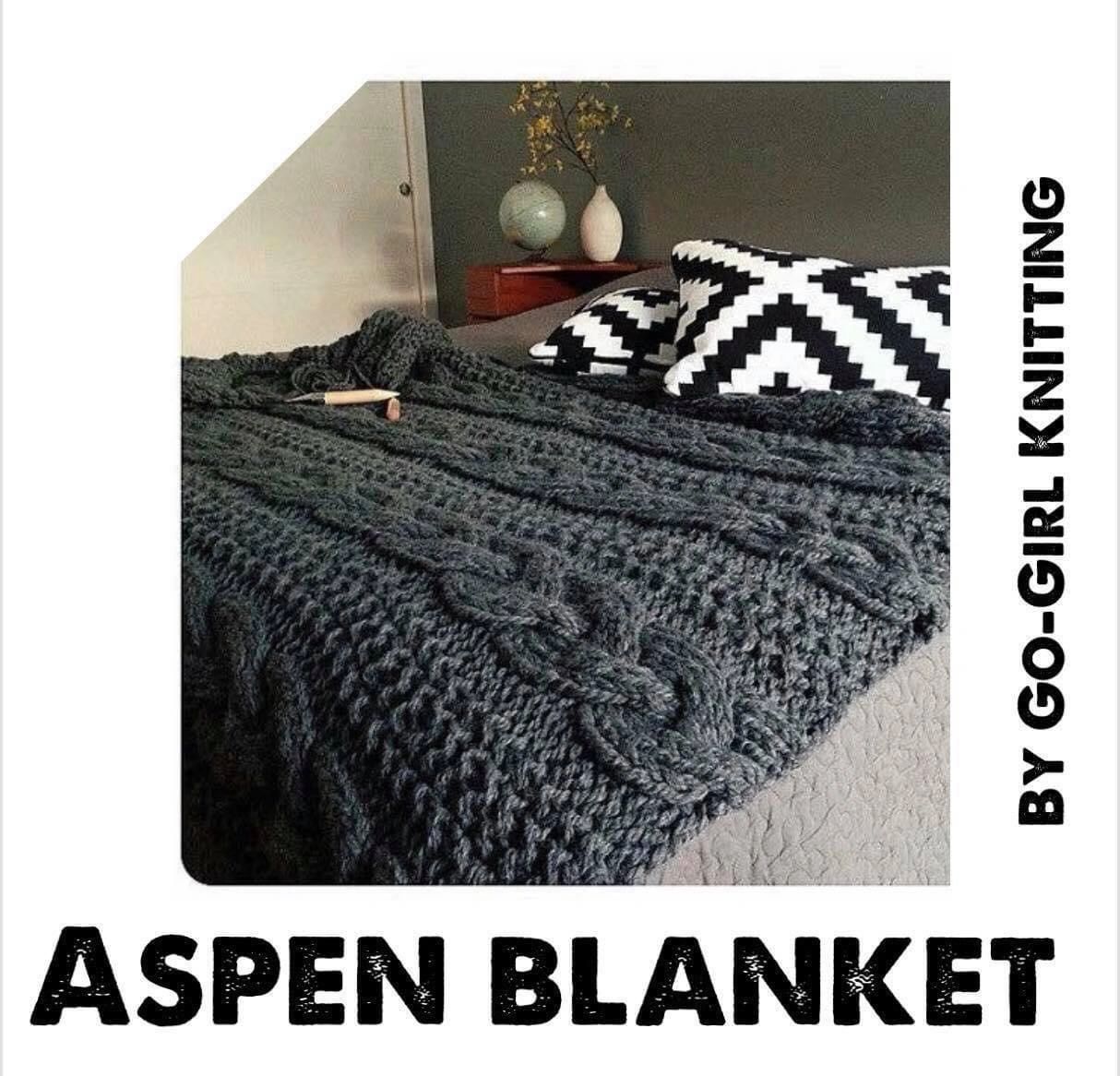 Cozy knitted Aspen Blanket on bed with patterned pillows.