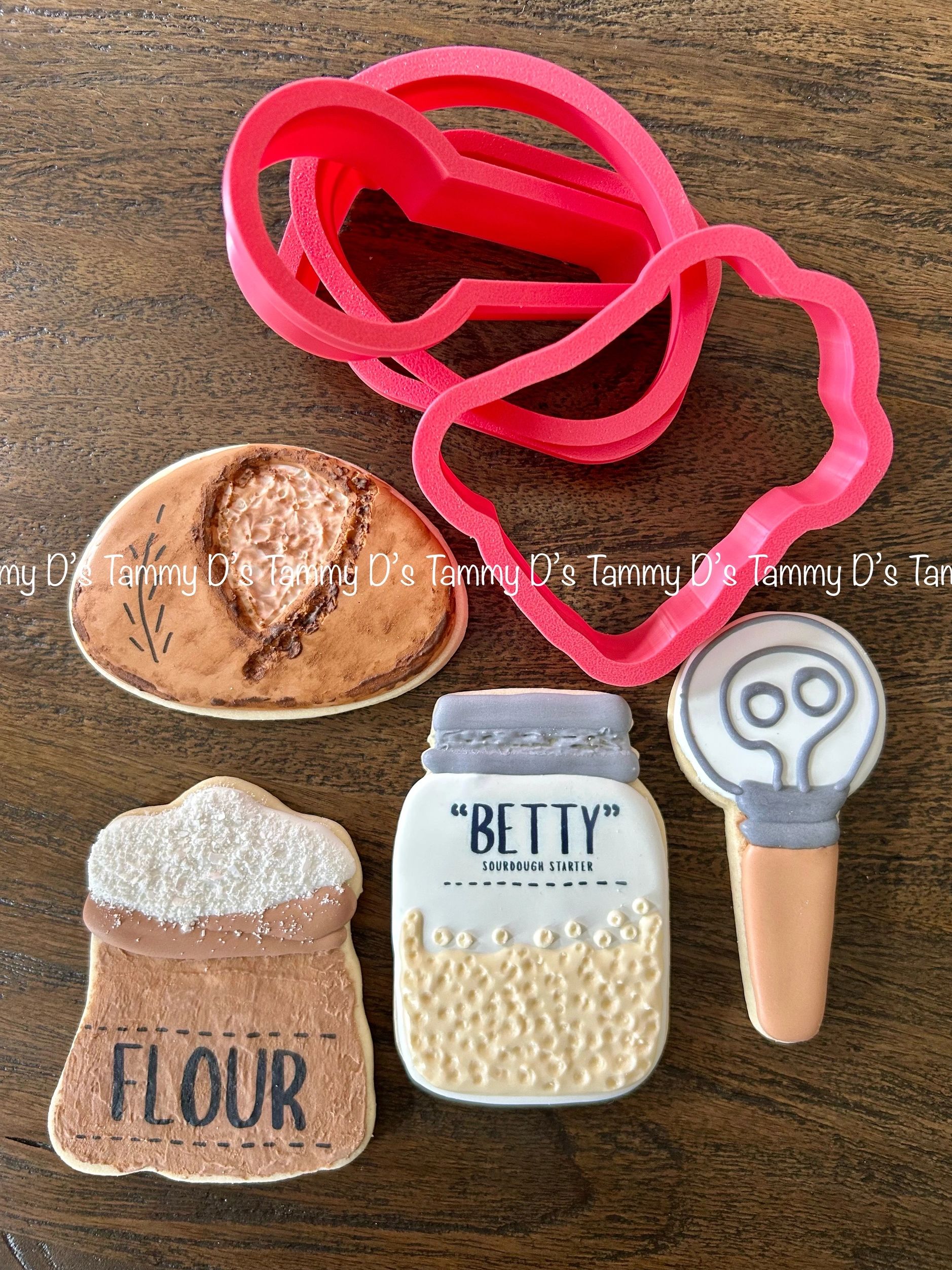 Baking-themed cookies and cookie cutters on a wooden table.