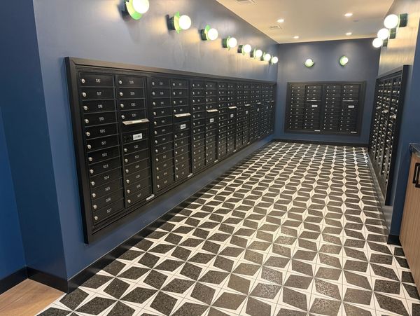 Modern mailroom with black mailboxes and patterned floor tiles.