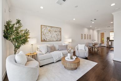 Bright modern living room with white furniture and wooden flooring.