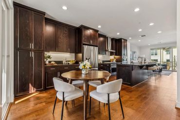 Modern kitchen with dark wood cabinets and a round dining table.