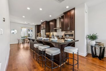 Modern kitchen with dark wood cabinets and a breakfast bar with stools.