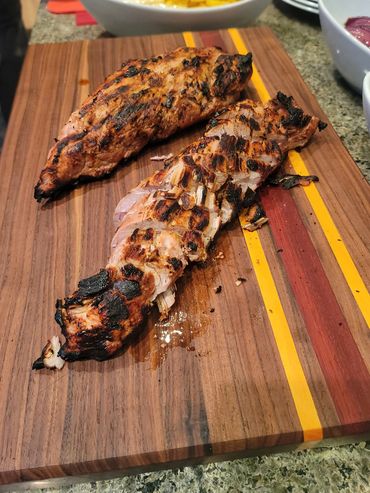 Cut Pork Tenderloin on unique cutting board that features Walnut, Padauk, and Yellow Heart stripes