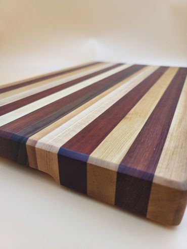 Close up view of exotic wood cutting board made with Curly Maple, Bubinga, Padauk, Cherry and Walnut