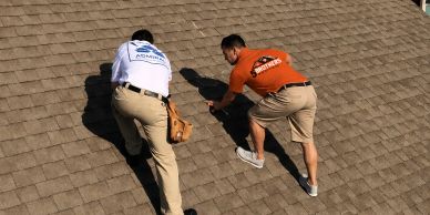 Two men inspecting a roof with tools.