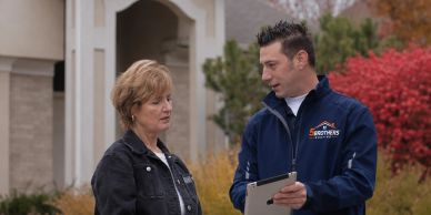 A man and woman discussing something outside a house.