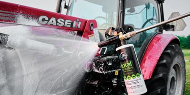 A tractor is being cleaned with foam spray from a canister.