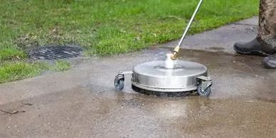 A surface cleaner cleaning a concrete pathway outdoors.