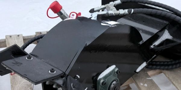 Heavy-duty mechanical attachment on a wooden pallet in snowy surroundings.