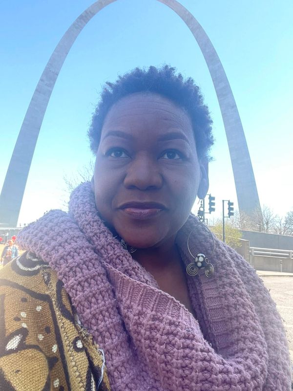 Woman taking a selfie with the Gateway Arch in the background.