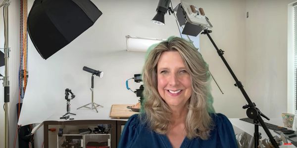 Smiling woman in front of a professional photography setup with lighting and camera equipment.