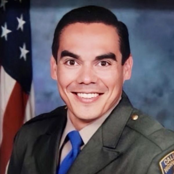 Smiling man in a California Highway Patrol uniform with an American flag background.