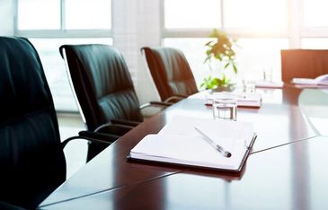 Empty conference room with black chairs and a notebook with pen on the table.