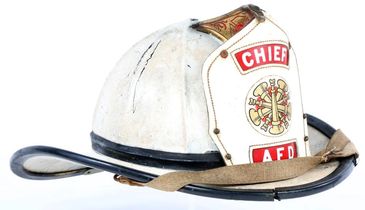 Vintage white firefighter helmet labeled 'CHIEF' and 'A.F.D.' with a leather strap.