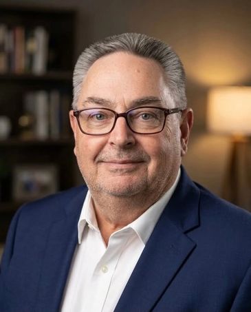 Professional headshot of a smiling man in glasses and a blue suit.