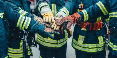 Firefighters joining hands in teamwork before a mission.