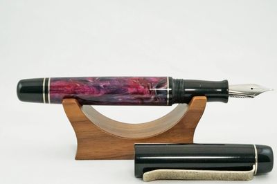 Elegant fountain pen with marbled purple body on wooden stand.