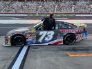 Race car number 73 on the track with a crowd in the stands.