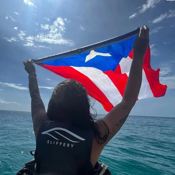 Person holding Puerto Rican flag on a jet ski in the ocean.