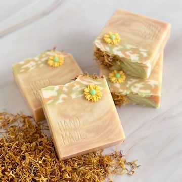 Soaps creamy in color with swirls of green, white creating a marbled effect, adorned yellow flowers.