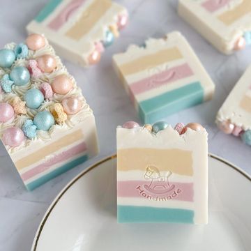 Bar soaps with pastel-colored layers in yellow, pink, and blue hues, and embedded pearls.