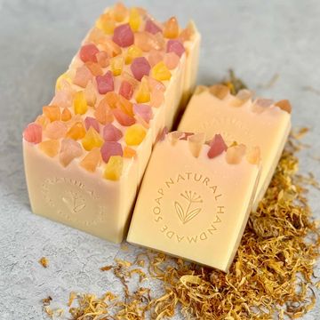 Natural handmade soaps with crystal gems on top, surrounded by dried calendula petals.