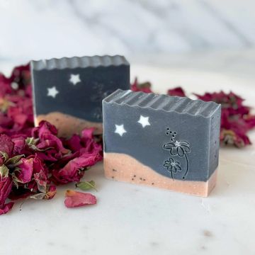 Charcoal & Rose Soap with a night sky design featuring white stars surrounded by dried rose petals.