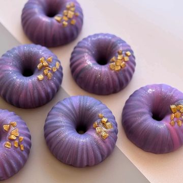 Handmade donut-shaped soap in purple tones with golden sprinkles, scented with lavender.