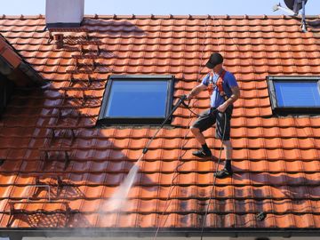 Roofer power washing on the roof. Maintenance on tile roof