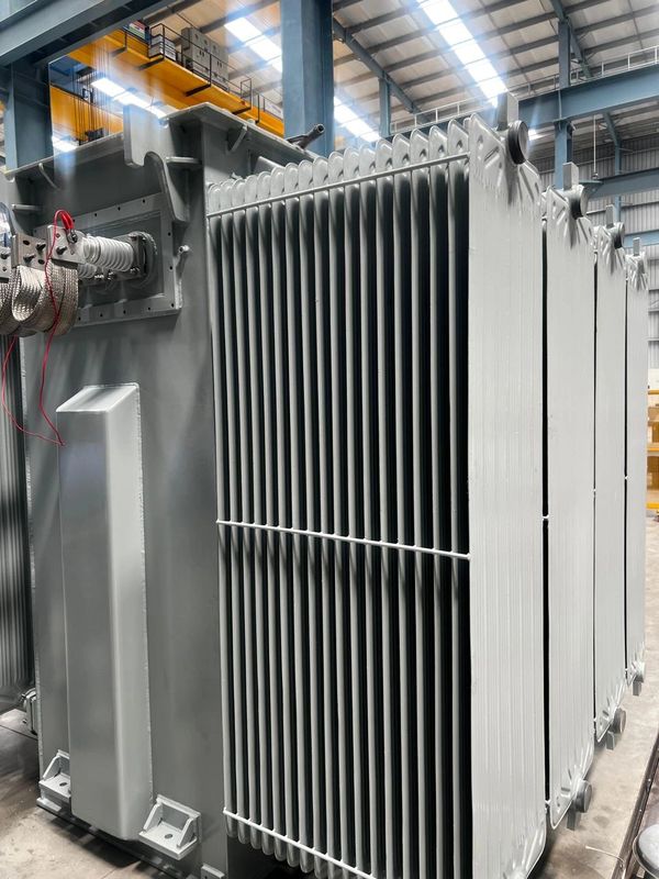 Large industrial transformer with cooling fins in a factory setting.