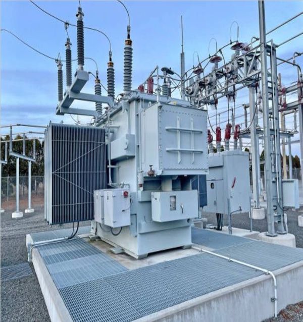Large electrical transformer at an outdoor substation with multiple insulators and wiring.