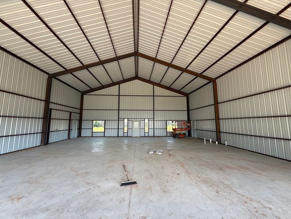 Empty metal building interior with concrete floor and broom.