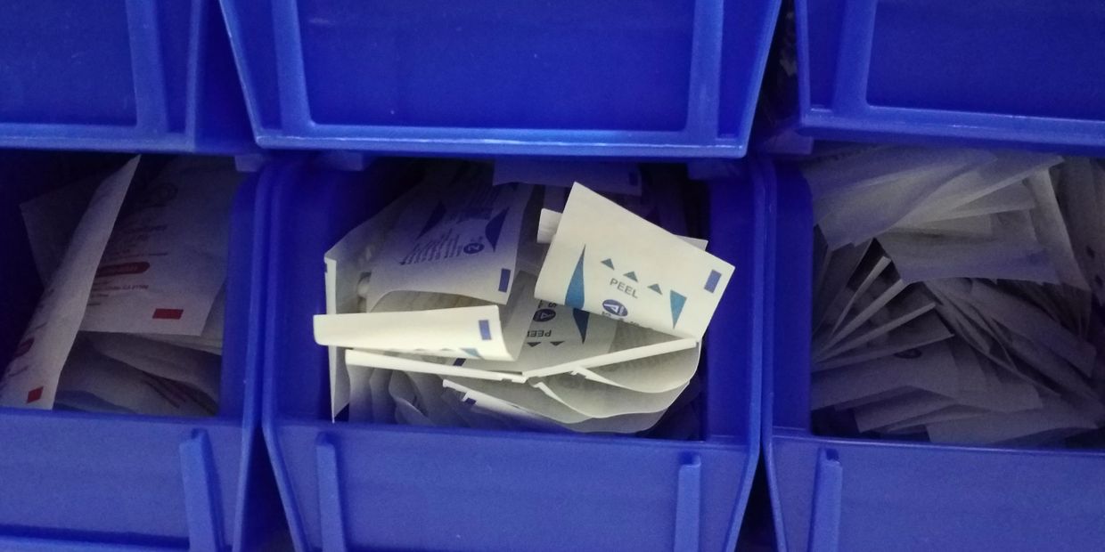 Close up of plastic bins storing assorted medical supplies.