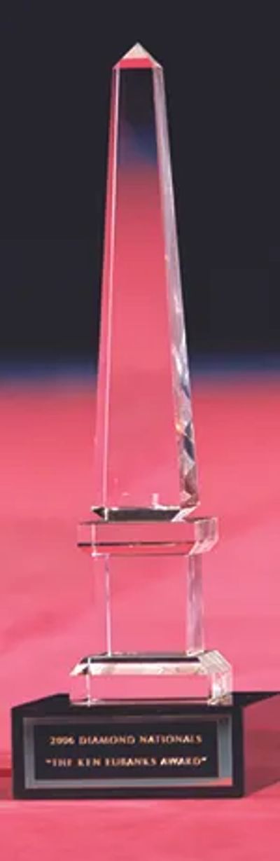 Clear crystal obelisk trophy with black base and gold inscription.