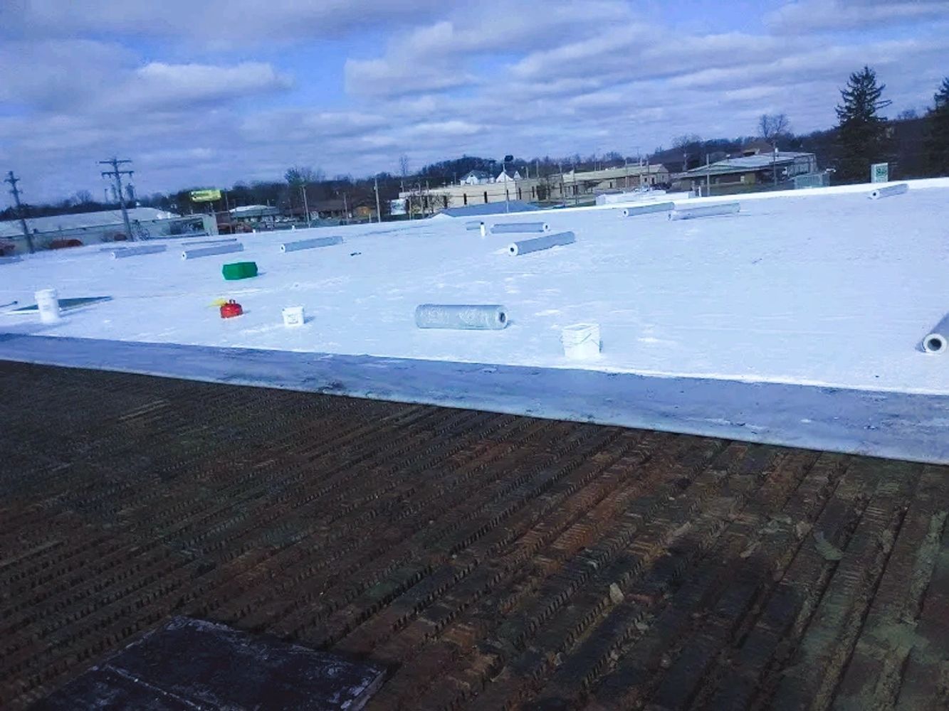 White roofing material being installed on a flat roof during daytime.