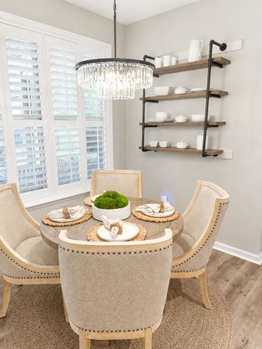 Elegant dining area with beige chairs and chandelier.