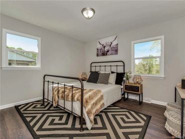 Cozy bedroom with iron bed frame and patterned rug under natural light.
