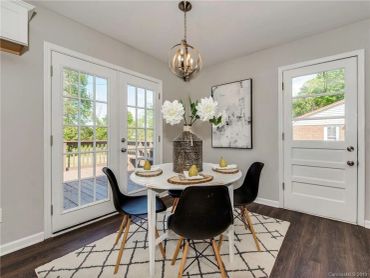 Modern dining area with black chairs and a round white table under a chandelier.