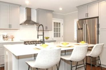White countertop on the kitchen island with bar stools providing seating and workspace.