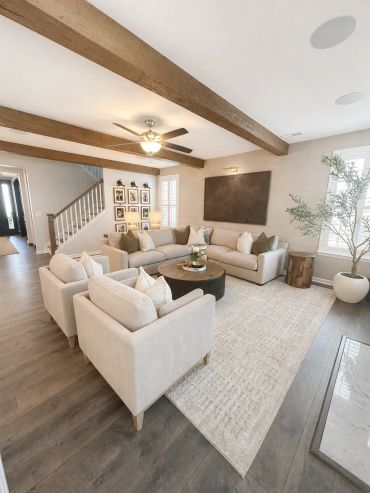Modern living room with neutral tones and wood beams.