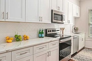 Updated kitchen for rent featuring a modern design, ample cabinet space, and a window with blinds.