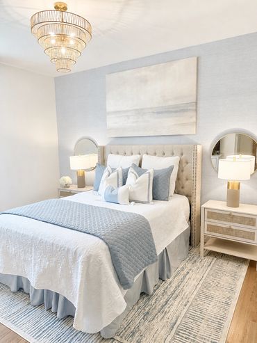 Elegant bedroom with soft blue and white tones and a chandelier.