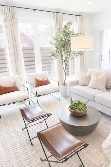 Bright living room with white furniture and leather stools.
