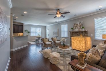 Light gray walls and dark hardwood floors in a living room with a ceiling fan and recessed lighting.
