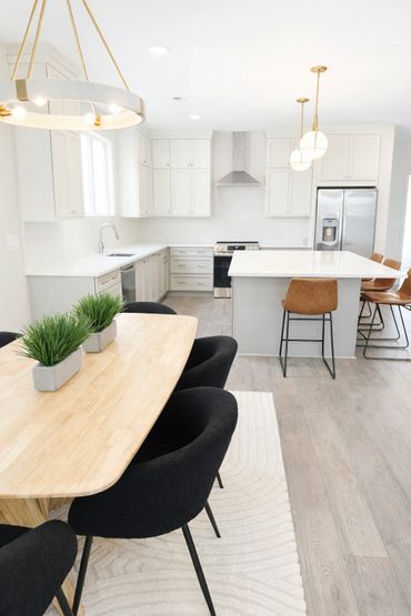 Bright modern kitchen with white cabinetry and a wooden dining table.