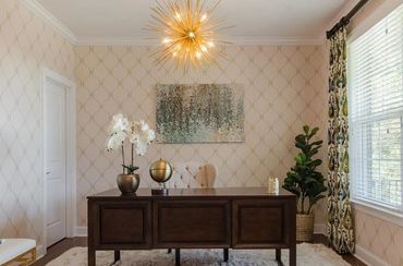 Modern home office with a large desk and statement lighting.